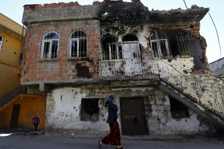 A woman walks past a building which was damaged during the security operations and clashes