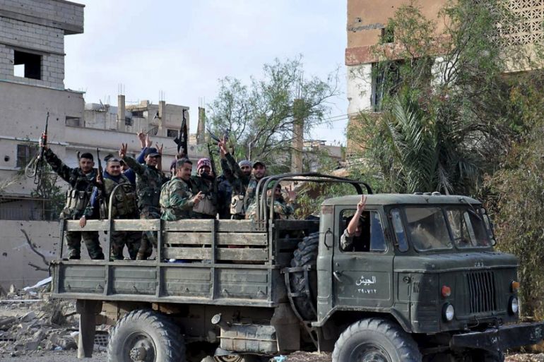 Forces loyal to Syria''s President Bashar al-Assad flash victory signs while riding on the back of a military truck in Palmyra city