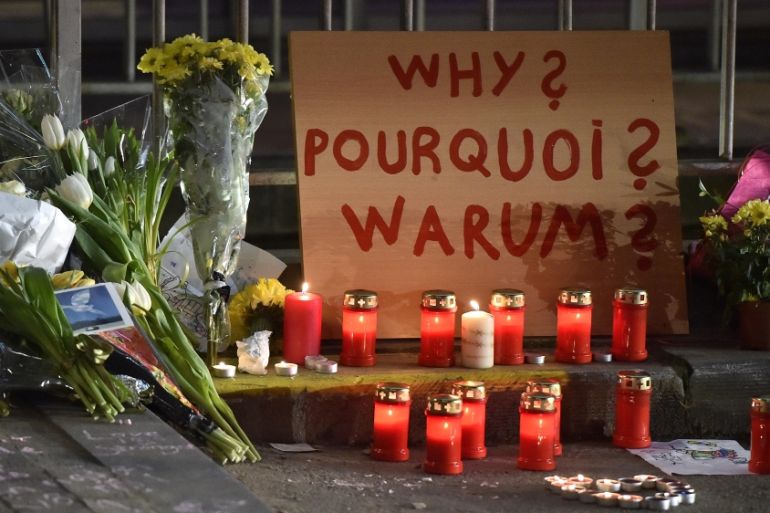 A sign reads "Why?" in English, French and Flemish behind candles and flowers near the Maelbeek metro station, in Brussels [AP]