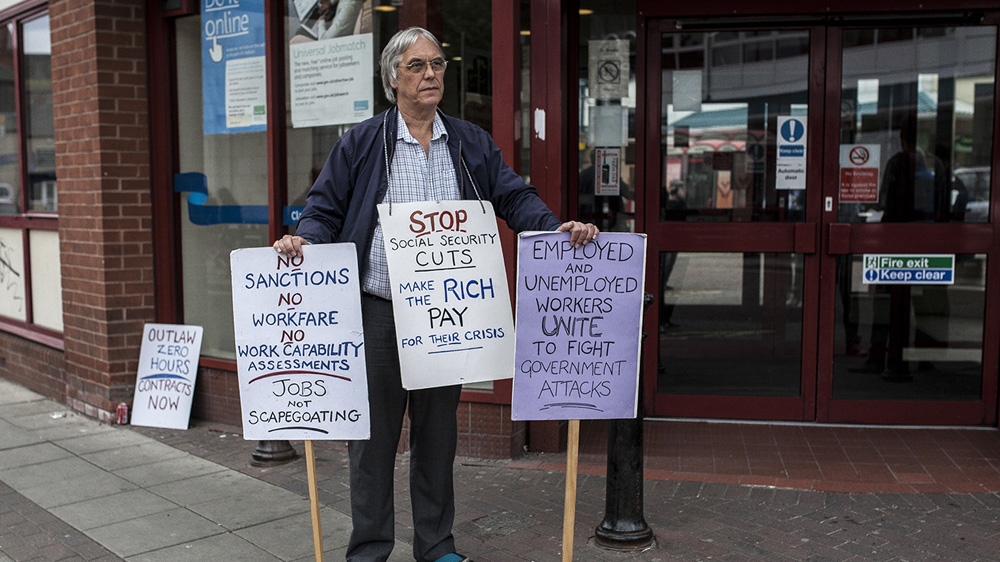 A member of Tameside Against The Cuts protests outside the Ashton-under-Lyne Jobcentre [David Shaw/Al Jazeera]