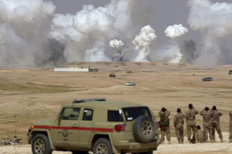 Soldiers watch as plumes of smoke rise following air bombardments during the Northern Thunder exercises, in Hafr Al-Batin