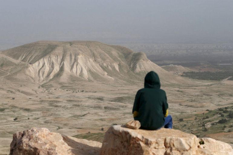 A Palestinian man sits on a rock at Jordan Valley near the West Bank city of Jericho [REUTERS]