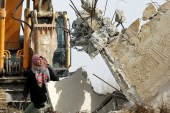 A Palestinian woman stands in front of Israeli bulldozers to stop them during the demolition of a house owned by Palestinians in the West Bank village of Biet Ula, January 2016. [EPA]