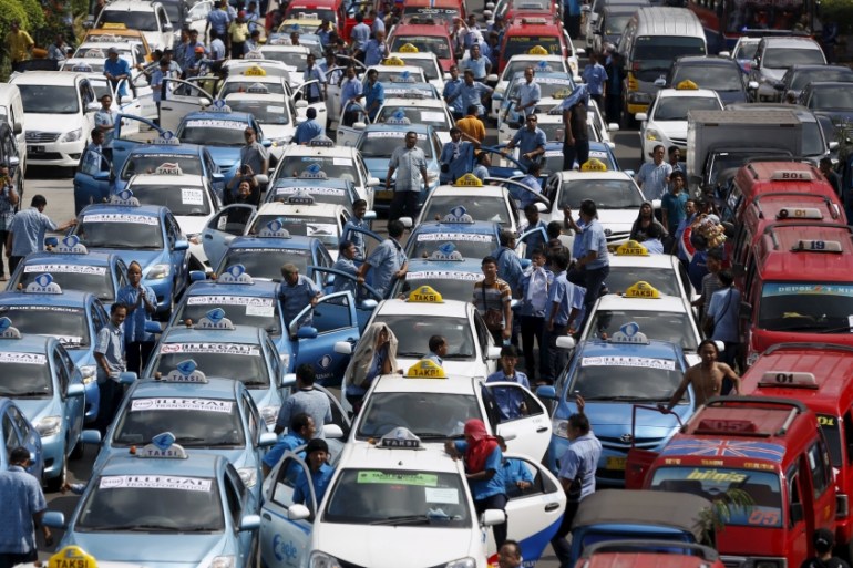 Taxis taking part in a protest rally to demand the government prohibits ride-hailing apps are seen stopped on a main road in Jakarta