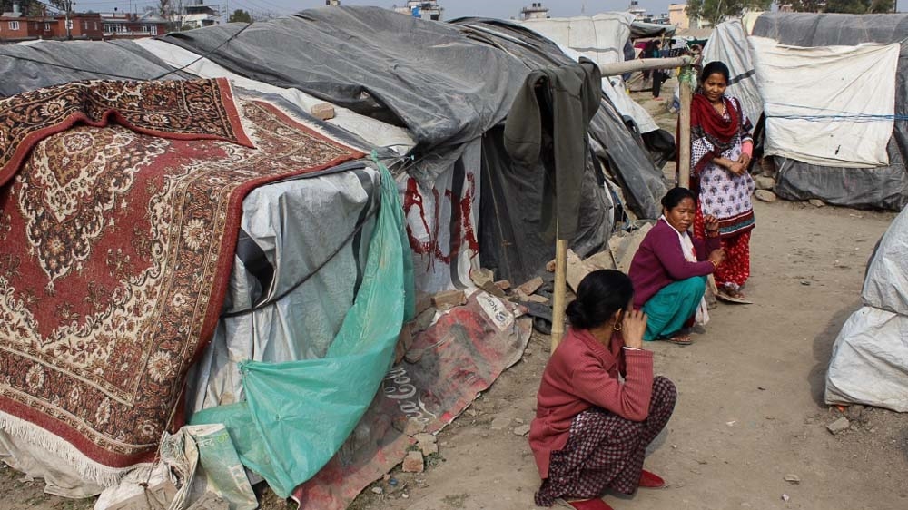 Quake survivors sit in front of their tents in Chuchepati, Kathmandu [Saif Khalid/Al Jazeera]