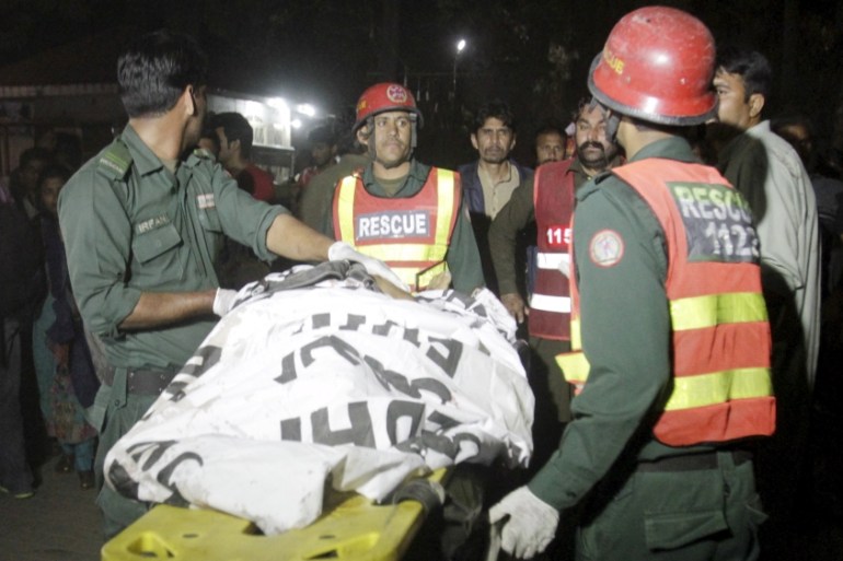 Rescue workers move a body from the site of a blast outside a public park in Lahore, Pakistan