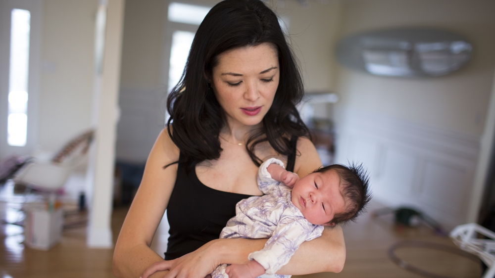 Ashlyn Nelson holds her four-week-old daughter, Suvi. Nelson is an economist and associate professor at Indiana University-Bloomington [James Brosher/Al Jazeera]  