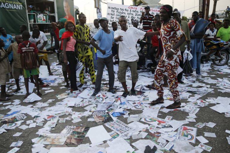 Supporters stand on presidential campaign flyers outside a rally venue, in the stade-Kouhounou district in Cotonou, Benin