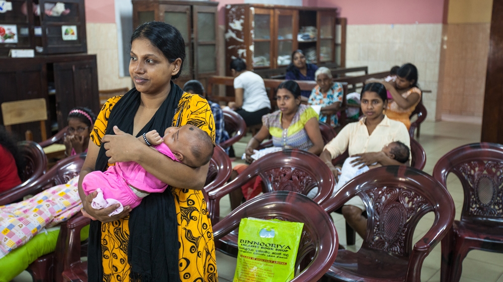 
A mother cradles her child at a clinic dedicated to babies just over a month old. Her baby is registered at this centre and will be carefully monitored until he turns five [Suda Shanmugaraja/Al Jazeera]

