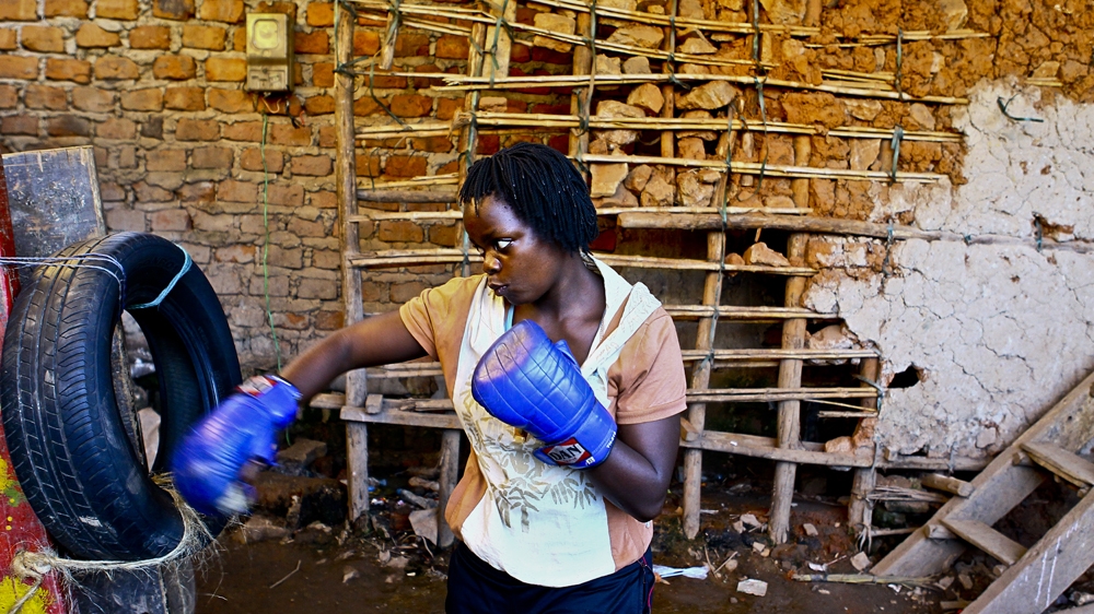 Hellen Baleke, the most experienced of the four boxers with 11 wins, four draws and a single loss to her name, practises her punches on an old car tyre, as they cannot afford actual punch bags [Edward Echwalu/Al Jazeera] 