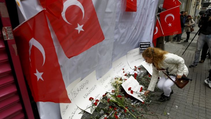 A woman places carnations and a candle at the scene of a suicide bombing at Istiklal street, a major shopping and tourist district, in central Istanbul