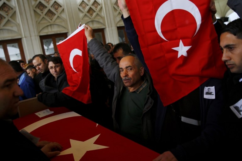Men hold Turkish flags over the coffin of a car bombing victim