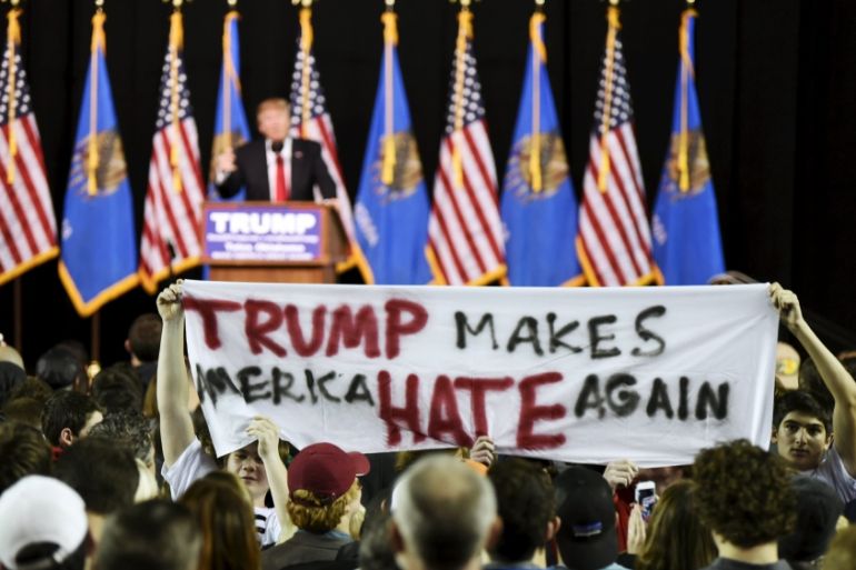 Protestors hold up a sign towards the crowd at a rally for U.S. Republican presidential candidate Donald Trump at Oral Roberts University in Tulsa, Oklahoma