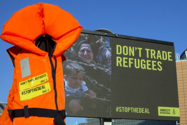 A life jacket hangs next to a giant screen during a demonstration outside EU headquarters in Brussels