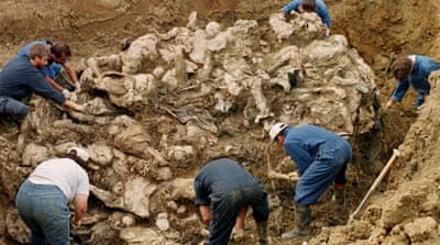 In this 1996 file photo, International War Crimes Tribunal investigators clear away soil and debris from dozens of Srebrenica victims buried in a mass grave in Bosnia-Herzegovina [AP]