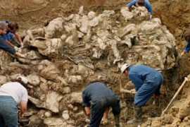 International War Crimes Tribunal investigators clearing away soil and debris