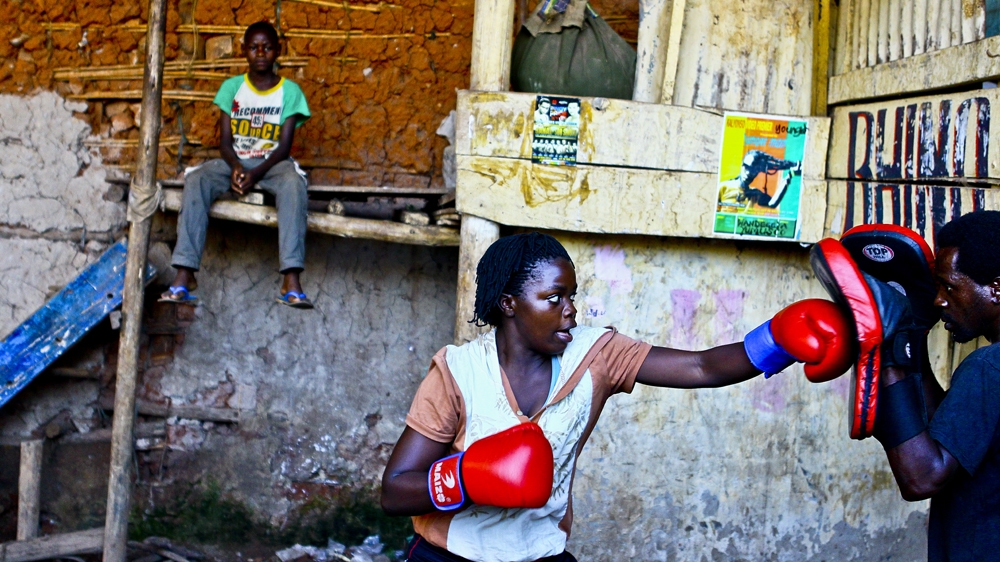 Hellen Baleke is taken through a training session by her trainer. Since the women are not in a position to hire a permanent coach, they are trained by part-time male boxers who take part of their commission from professional fights. The only way the women earn any money from their sweat is through the mostly locally organised bouts [Edward Echwalu/Al Jazeera] 
