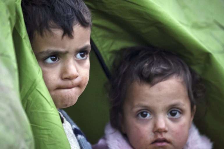 Children peer from a tent at a northern Greek border station [AP]