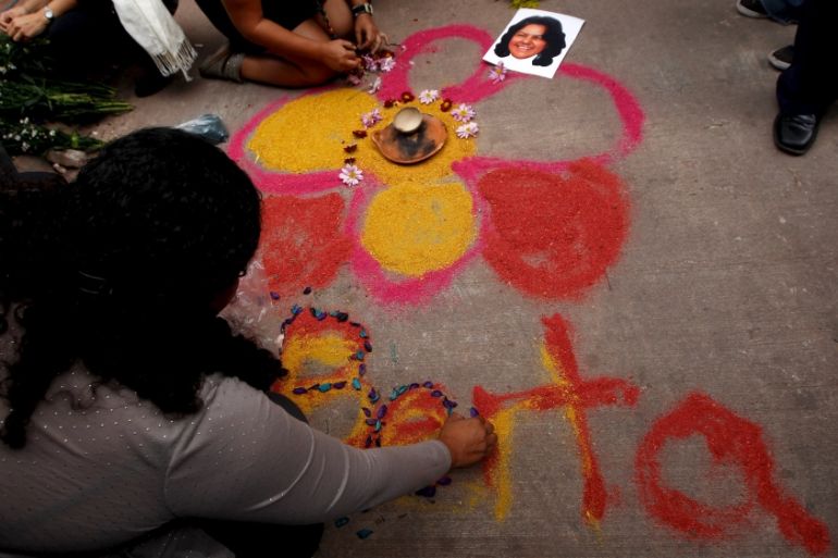 Activists draw a flower on the floor with chalk as part of a makeshift altar for slain environmental rights activist Berta Caceres during a protest outside the morgue in Tegucigalpa