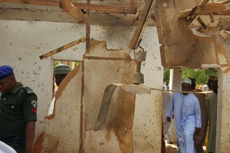 People inspect a damaged mosque following a suicide bomb explosion in Maiduguri