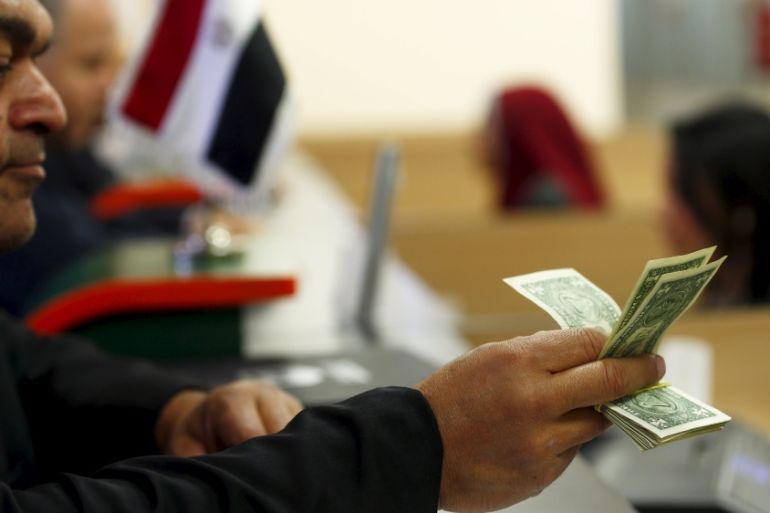 A customer checks his US dollar notes in a bank in Cairo, Egypt [REUTERS]