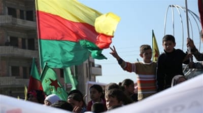 Kurdish children flash the sign for victory next to a flag of the PYD during a demonstration against the exclusion of Syrian Kurds from the Geneva talks in Qamishli [Getty]