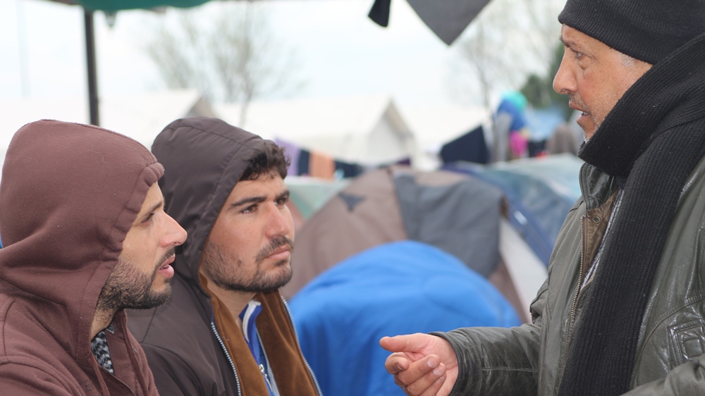 Walid Jemu, left, talks with other Syrian refugees at a petrol station 20km from the Greek border with former Yugoslav Macedonia [John Psaropoulos/Al Jazeera]
