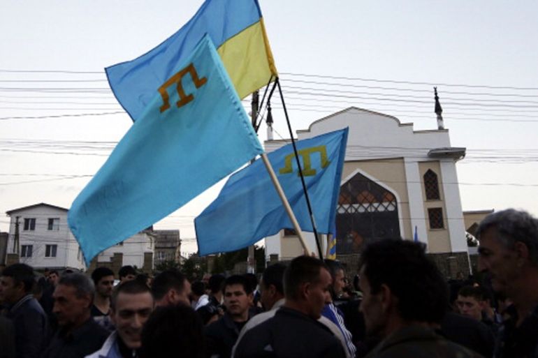 Crimean Tatars hold Ukrainian and Tatar flags as they attend a memorial ceremony marking the 70th anniversary of the deportation of Tatars from Crimea, near a Mosque in Simferopol in 2014 [Getty]