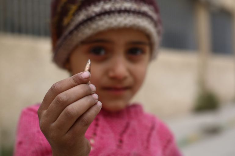 A girl shows a sniper bullet that was found in the school yard in the rebel-held city of Douma, on the outskirts of Damascus, Syria [EPA]