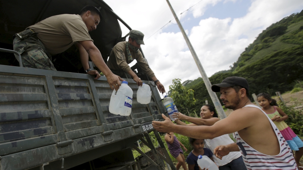 Residents receive donations of bottled water from Ecuador soldiers along a road after evacuating from their homes in Ecuador [Henry Romero/Reuters]