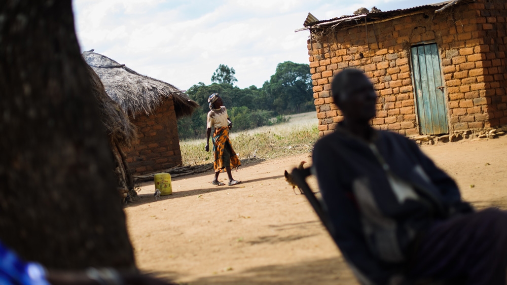 A woman walks through the compound of Kimweli Mbithuka and his wife, Naomi Nziula Kimweli. Kimweli was castrated during his time in detention, and Naomi, who was pregnant at the time, was assaulted with a bottle, causing her to miscarry [Phil Moore/Al Jazeera]