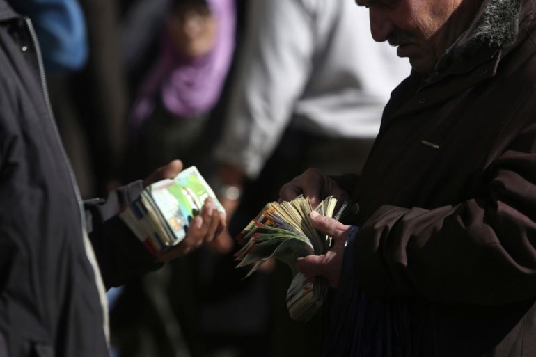 Palestinian money changers count money on a street in the West Bank city of Ramallah