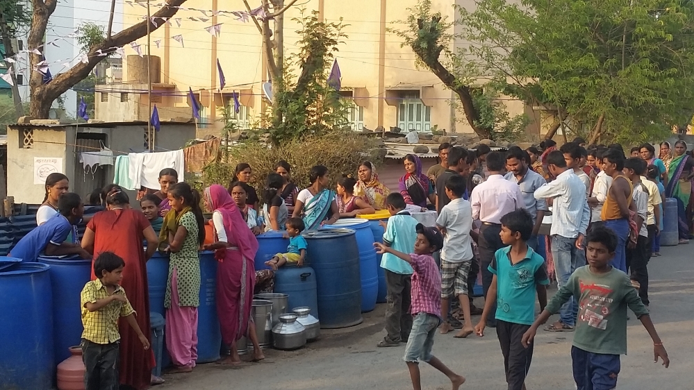 Residents line up for water, the first time they will be receiving the supply in 15 days [Faiz Jamil/Al Jazeera]