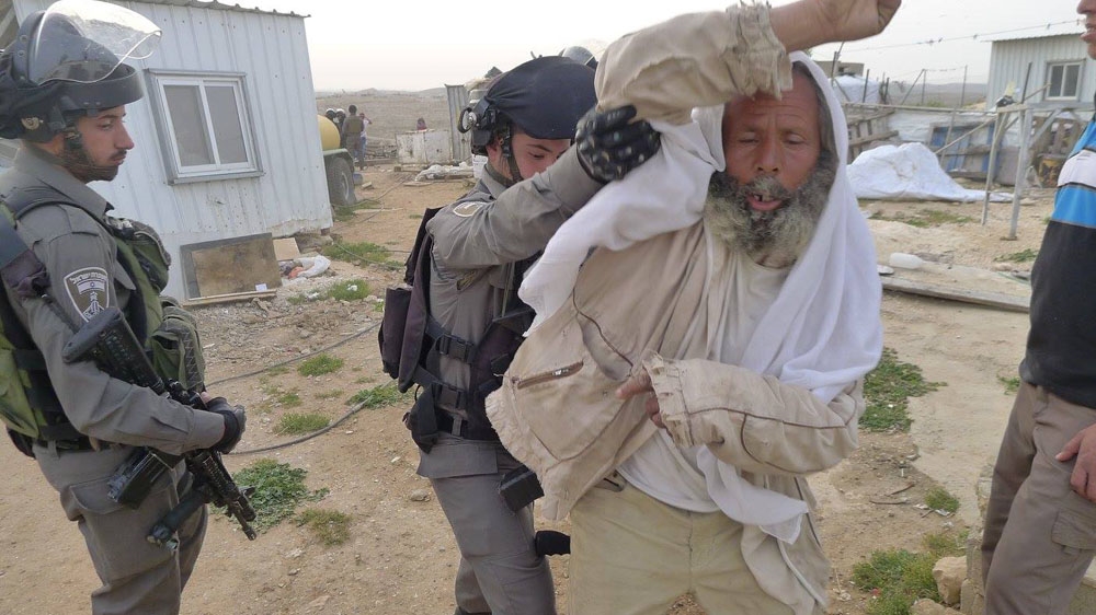 Hathaleen, the patriarch of the Bedouin community of Umm al-Khair, is pushed by an Israeli soldier as Israeli bulldozers destroy their homes [Tariq and Eid Hathaleen/Al Jazeera]