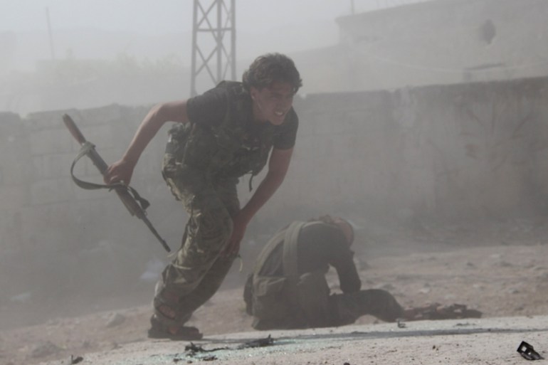A rebel fighter from the Ahrar al-Sham Islamic Movement carries his weapon as he moves past an injured fellow fighter during what they said were clashes with forces loyal to Syria''s President Bashar a