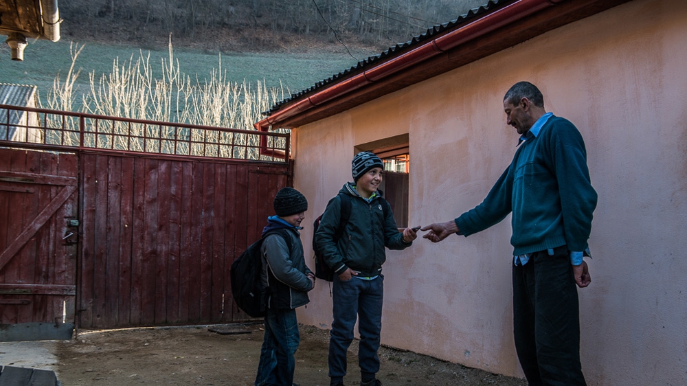 Sorin Boboc's sons, Sergiu and Oliver, drop his mobile phone at his brother-in-law's home on their way to school so that it can be charged [Felix Gaedtke/Al Jazeera] 