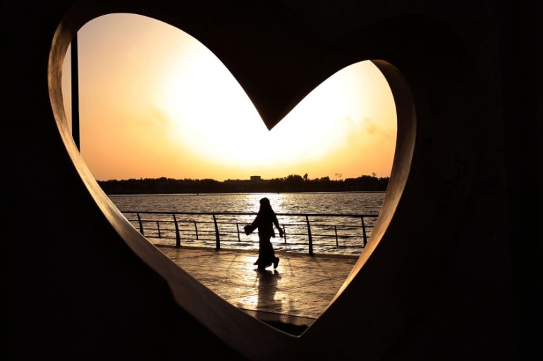 A Saudi woman seen through a heart-shaped statue walks along an inlet of the Red Sea in Jeddah, Saudi Arabia [AP]