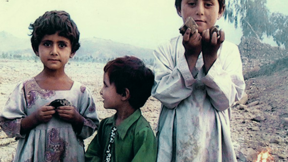 Three children in North Waziristan are holding remnants of a drone-fired missile and rubble from their neighbour's house [Noor Behram Copyright @ Flimmer Film 2014]