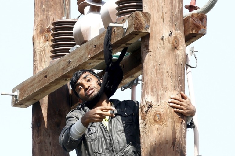 Pakistani migrant threatens to hang himself from a utility pole during a demonstration inside the Moria registration centre on the Greek island of Lesbos