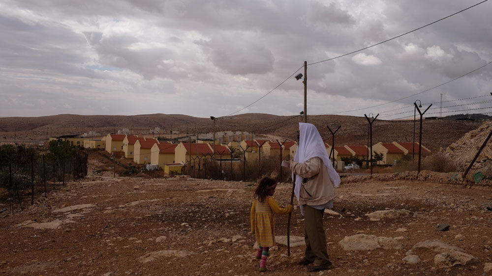 Suleiman Hathaleen and his granddaughter walk along the fence separating their homes from the Israeli settlement of Carmel, which was built on their own land [Dalia Hatuqa/Al Jazeera]