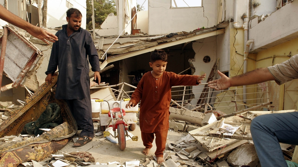 A father and child in the rubble of their damaged home the morning after a car bomb attack on the Criminal Investigation Department in Karachi [Mohammed Athar Khan/The Express Tribune] 