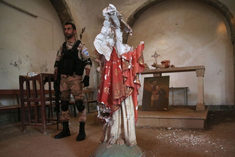 A Christian militiaman stands near the broken body of a statue of Christ in the 13th century St. Jacob''s Church near the frontline with ISIL fighters in Telskuf, northern Iraq [Getty]