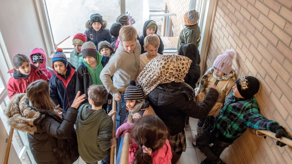 Swedish students walk through a group of refugee children in a school in 2016 [File: Gallo/Getty]
