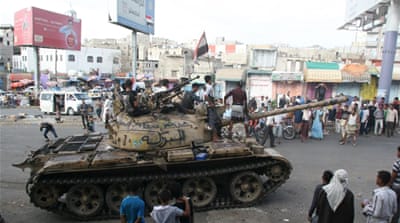 Pro-government fighters ride on a tank in the Bir Basha neighbourhood after they took the area from Houthi fighters in Yemen's southwestern city of Taiz [Reuters]