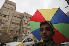 A boy with an umbrella hat walks in an old quarter of Yemen''s capital Sanaa [REUTERS]