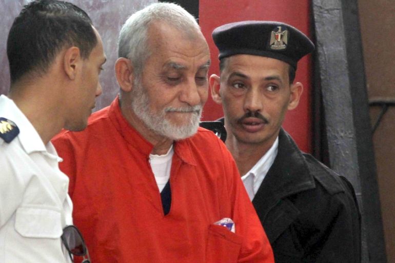 Mohamed Badie, top leader of Egypt''s outlawed Muslim Brotherhood, is led by police to talk during a trial hearing alleging his involvement in a 2013 attack on a Port Said police station at a court