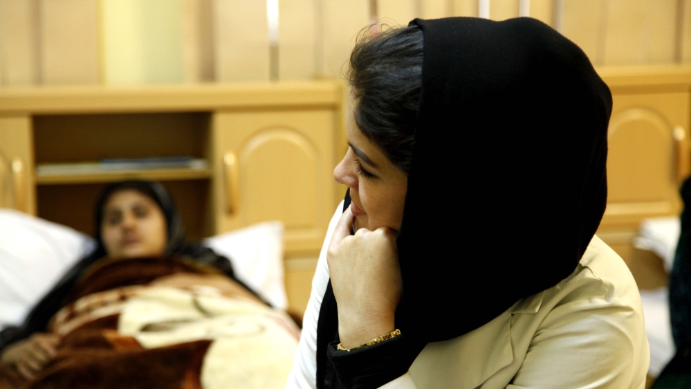 A nurse sits with one of the clinic's long-term patients [Mariam Alimi/Al Jazeera] 