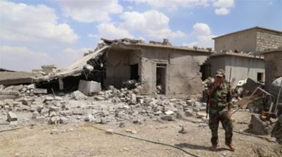 Kurdish fighter stands in front of a destroyed house in Mufti village, near Mosul [Al Jazeera]
