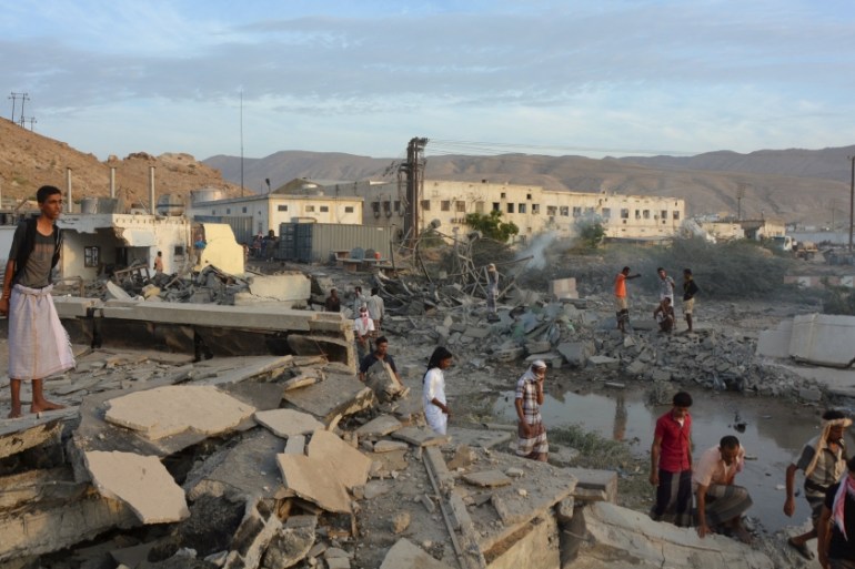 People inspect damage at a site hit by Saudi-led air strikes in the al Qaeda-held port of Mukalla city in southern Yemen