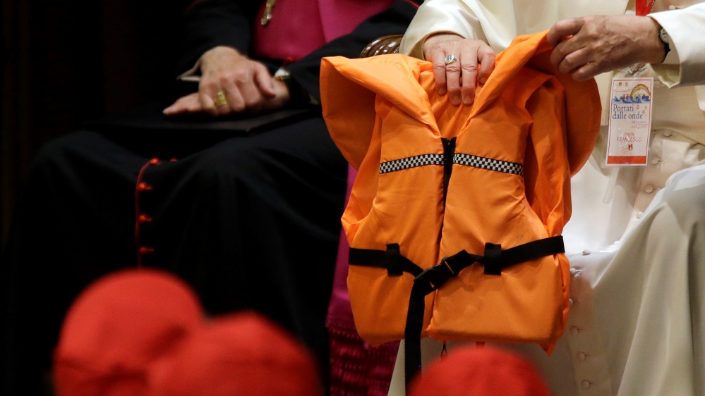 Pope Francis shows the children an orange life jacket given to him by a Spanish rescuer working to save lives in the Mediterranean [Reuters]